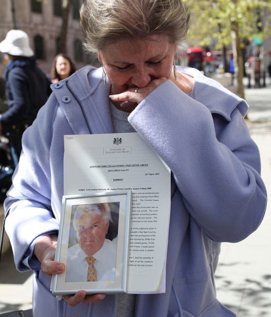 Karen Wilson, widow of postmaster Julian Wilson who died in 2016, holds a photograph of her husband outside the Royal Courts of Justice, London, after his conviction was overturned by the Court of Appeal (Yui Mok/PA)
